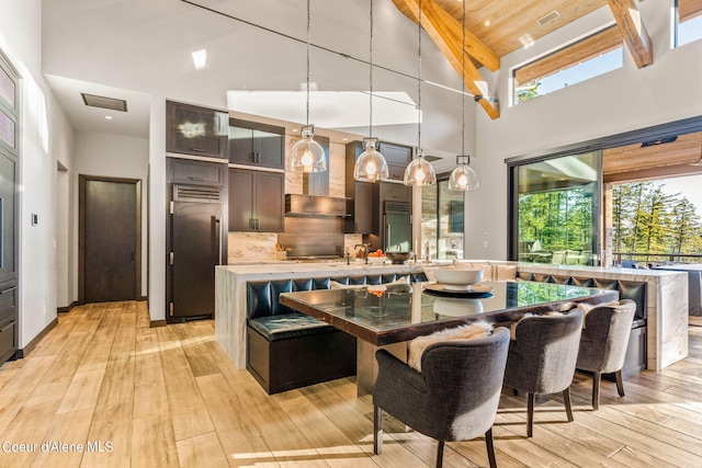6361 S Cormorant Ct, Harrison, ID 83833 - kitchen with built in refrigerator, light wood-style floors, wall chimney range hood, hanging light fixtures, and a kitchen island with sink