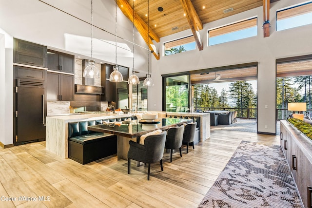 6361 S Cormorant Ct, Harrison, ID 83833 - kitchen featuring high quality fridge, high vaulted ceiling, light countertops, wall chimney range hood, and light wood-style floors