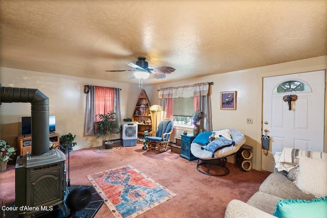 301 Third St, Osburn, ID 83849 - living room featuring carpet, a wood stove, ceiling fan, and a textured ceiling