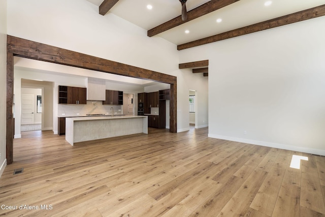 1456 E Ezra Ave, Hayden, ID 83835 - unfurnished living room with beamed ceiling, a sink, light wood-type flooring, baseboards, and recessed lighting