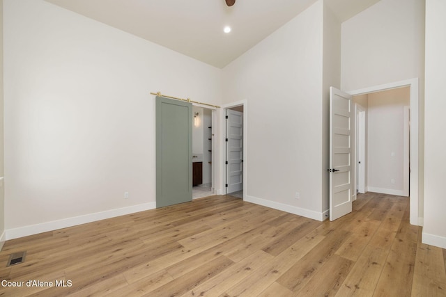 1456 E Ezra Ave, Hayden, ID 83835 - unfurnished bedroom with a towering ceiling, light wood-style flooring, baseboards, and connected bathroom