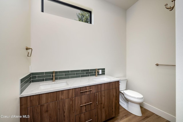 1456 E Ezra Ave, Hayden, ID 83835 - bathroom with double vanity, toilet, wood finished floors, baseboards, and decorative backsplash