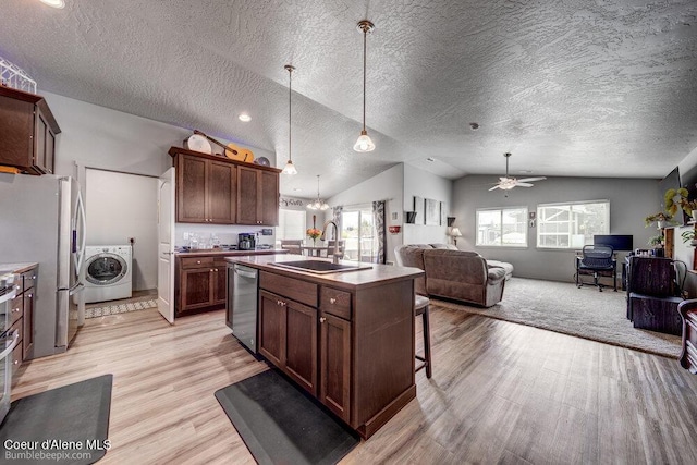 7156 W Christine St, Rathdrum, ID 83858 - kitchen with washer / dryer, a sink, stainless steel appliances, light wood-style floors, and open floor plan