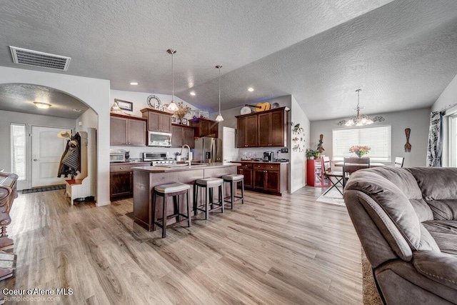 7156 W Christine St, Rathdrum, ID 83858 - kitchen featuring open floor plan, appliances with stainless steel finishes, a chandelier, a kitchen breakfast bar, and a textured ceiling