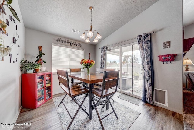 7156 W Christine St, Rathdrum, ID 83858 - dining room with a textured ceiling, light wood-style flooring, a chandelier, baseboards, and vaulted ceiling