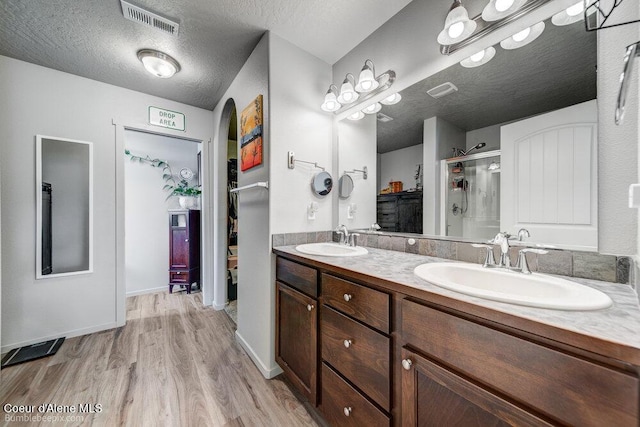 7156 W Christine St, Rathdrum, ID 83858 - bathroom featuring wood finished floors, a shower stall, double vanity, and a textured ceiling