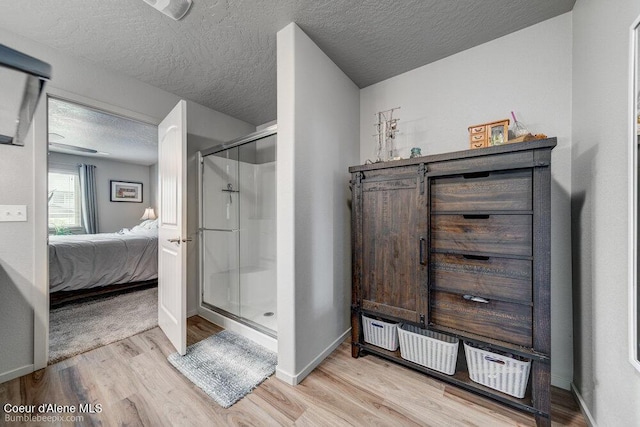 7156 W Christine St, Rathdrum, ID 83858 - ensuite bathroom featuring a stall shower, wood finished floors, a textured ceiling, and baseboards