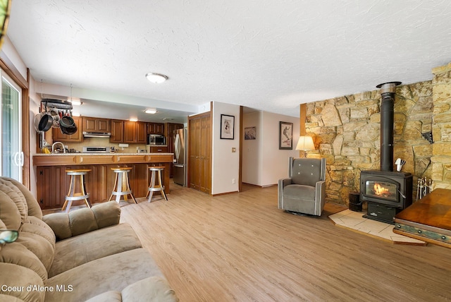 272 Hidden Springs Rd, Sandpoint, ID 83864 - living area featuring light wood-style floors, a textured ceiling, a wood stove, and baseboards