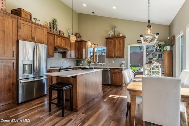 1803 W Felton Dr, Coeur Dalene, ID 83814 - kitchen featuring stainless steel appliances, under cabinet range hood, dark wood-type flooring, backsplash, and a center island