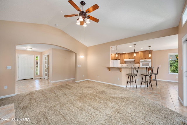 10016 N Zack Ct, Hayden, ID 83835 - living room featuring arched walkways, light tile patterned floors, light colored carpet, ceiling fan, and lofted ceiling