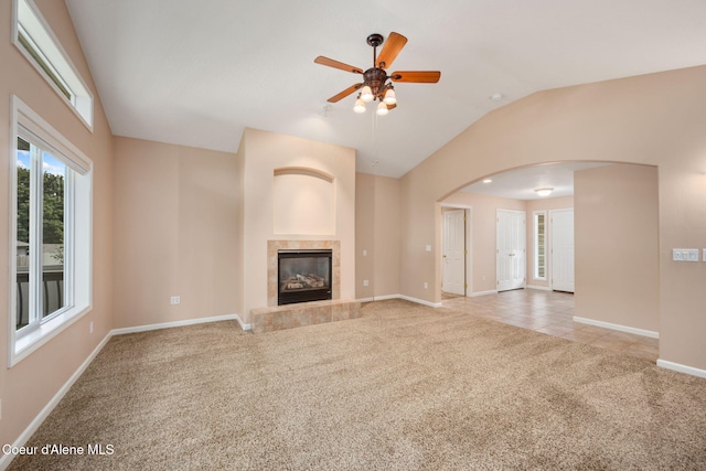10016 N Zack Ct, Hayden, ID 83835 - unfurnished living room featuring carpet, arched walkways, vaulted ceiling, ceiling fan, and a tile fireplace