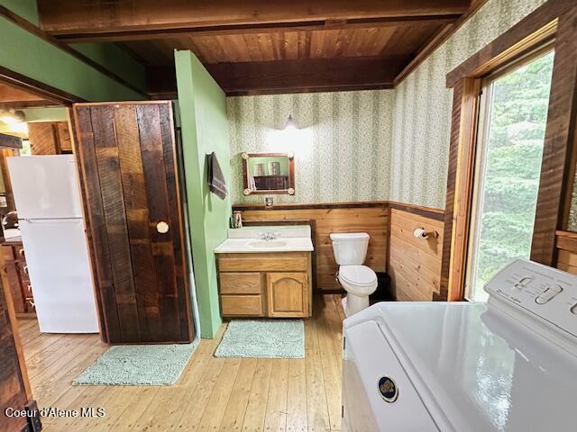 474 NW Fork Santa Creek Rd, Emida, ID 83861 - full bathroom with washer / dryer, wallpapered walls, toilet, vanity, and wood-type flooring