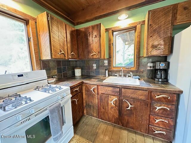 474 NW Fork Santa Creek Rd, Emida, ID 83861 - kitchen with white gas range oven, a sink, wooden ceiling, light wood-style flooring, and backsplash