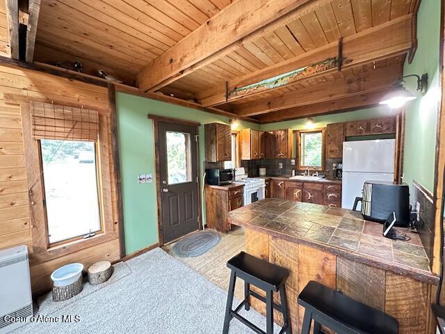 474 NW Fork Santa Creek Rd, Emida, ID 83861 - kitchen with white appliances, wooden ceiling with exposed beams, tile counters, a breakfast bar, and a sink