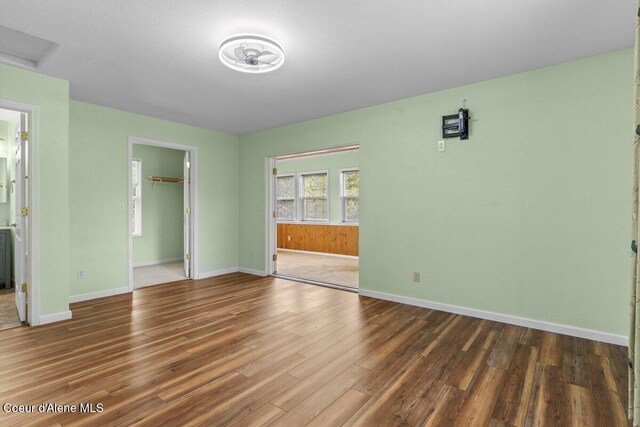 31716 N Middle Ave, Spirit Lake, ID 83869 - unfurnished bedroom with wood finished floors, a closet, baseboards, a walk in closet, and ensuite bath