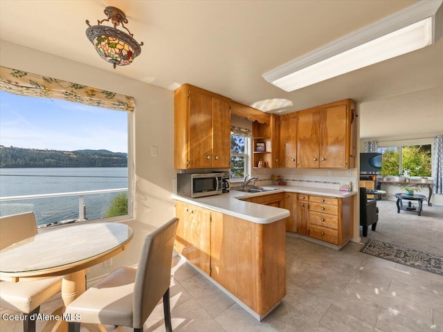 1824 W Cottonwood Rd, Worley, ID 83876 - kitchen featuring a peninsula, stainless steel microwave, brown cabinetry, and light countertops