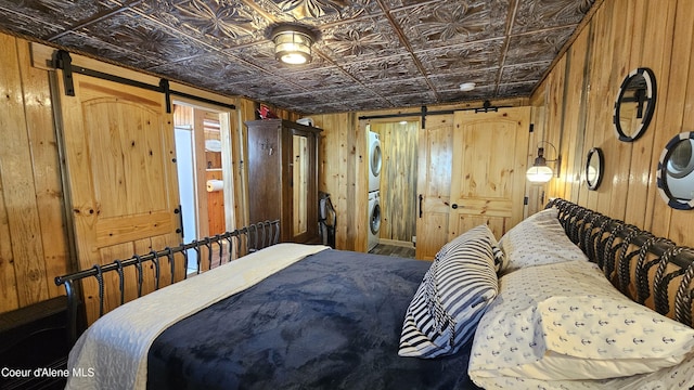 33671 N Macdonalds Unit 2Nd, Dock, Bayview, ID 83803 - bedroom with a barn door, stacked washing machine and dryer, wood walls, and an ornate ceiling