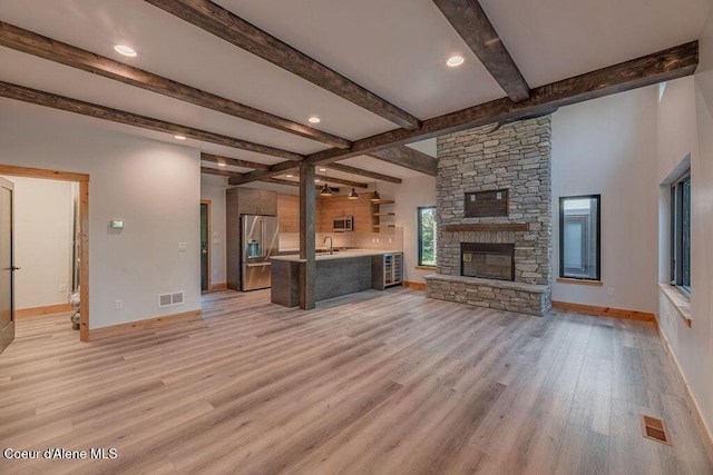 74 Wedge Ct, Priest Lake, ID 83856 - unfurnished living room with a sink, light wood finished floors, baseboards, beamed ceiling, and a fireplace