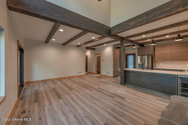 74 Wedge Ct, Priest Lake, ID 83856 - unfurnished living room with light wood-style floors, beverage cooler, beamed ceiling, recessed lighting, and baseboards