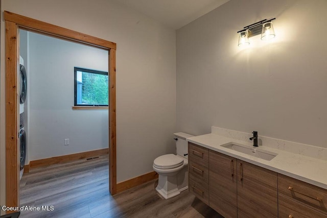 74 Wedge Ct, Priest Lake, ID 83856 - bathroom with stacked washing machine and dryer, wood finished floors, vanity, toilet, and baseboards