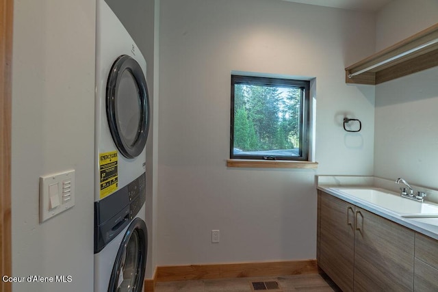 74 Wedge Ct, Priest Lake, ID 83856 - washroom with stacked washer and clothes dryer, light wood-style floors, and cabinet space