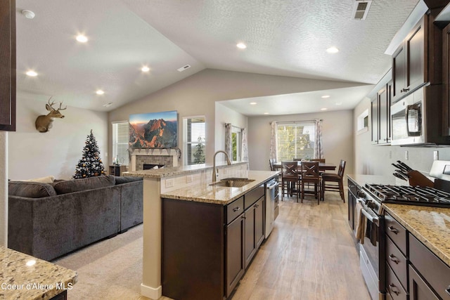 4447 N Connery Loop, Post Falls, ID 83854 - kitchen featuring stainless steel appliances, a sink, open floor plan, dark brown cabinetry, and vaulted ceiling