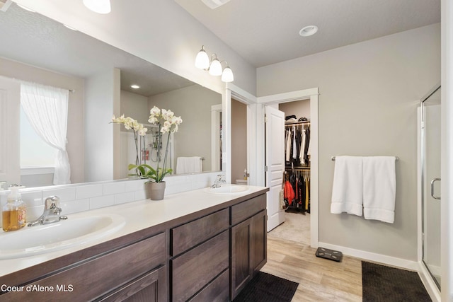 4447 N Connery Loop, Post Falls, ID 83854 - full bath featuring wood finished floors, double vanity, a stall shower, a spacious closet, and baseboards