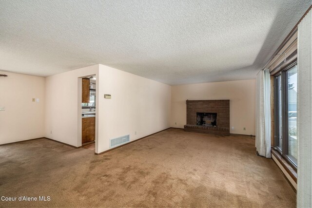 407 W Musket Ave, Post Falls, ID 83854 - unfurnished living room with carpet flooring, a textured ceiling, a fireplace, and baseboards