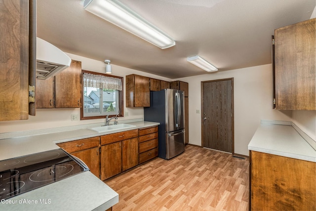 407 W Musket Ave, Post Falls, ID 83854 - kitchen featuring extractor fan, a sink, freestanding refrigerator, light wood-type flooring, and light countertops