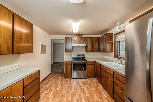 407 W Musket Ave, Post Falls, ID 83854 - kitchen featuring stainless steel appliances, a sink, light wood-type flooring, under cabinet range hood, and light countertops