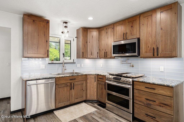 3623 W Hillcrest Cir, Coeur Dalene, ID 83815 - kitchen with appliances with stainless steel finishes, a sink, brown cabinetry, wood finished floors, and backsplash
