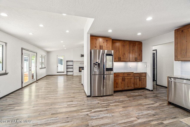 3623 W Hillcrest Cir, Coeur Dalene, ID 83815 - kitchen featuring appliances with stainless steel finishes, wood finished floors, a textured ceiling, brown cabinetry, and tasteful backsplash