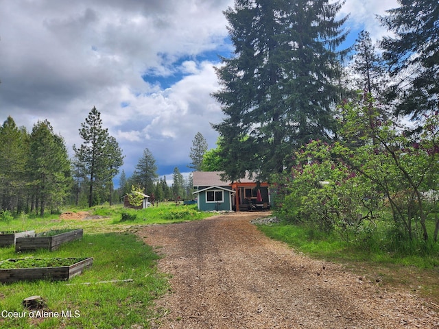 16488 N Atlas Rd, Rathdrum, ID 83858 - view of front of home with a vegetable garden, dirt driveway, and an outdoor structure