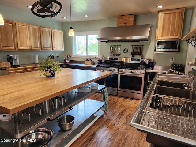16488 N Atlas Rd, Rathdrum, ID 83858 - kitchen featuring appliances with stainless steel finishes, wall chimney exhaust hood, wooden counters, recessed lighting, and wood finished floors