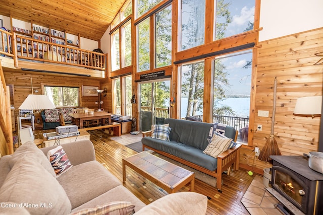 90 Bartoo Is Shr, Priest Lake, ID 83856 - living room featuring high vaulted ceiling, a wood stove, wood walls, a water view, and wooden ceiling