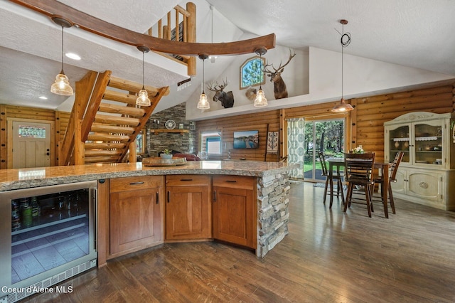 27294 N Clagstone Rd, Athol, ID 83801 - kitchen with beverage cooler, high vaulted ceiling, dark wood-style flooring, log walls, and decorative light fixtures
