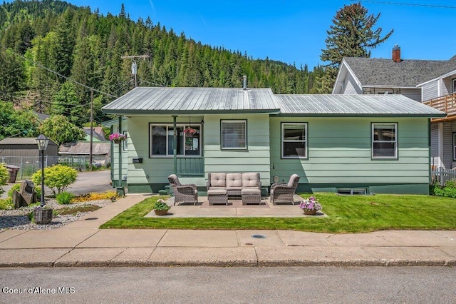 103 3rd St, Wallace, ID 83873 - view of front of house with outdoor lounge area, a forest view, metal roof, and a patio area