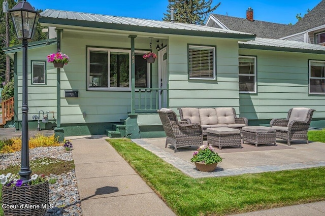 103 3rd St, Wallace, ID 83873 - rear view of house with metal roof, an outdoor hangout area, and a patio