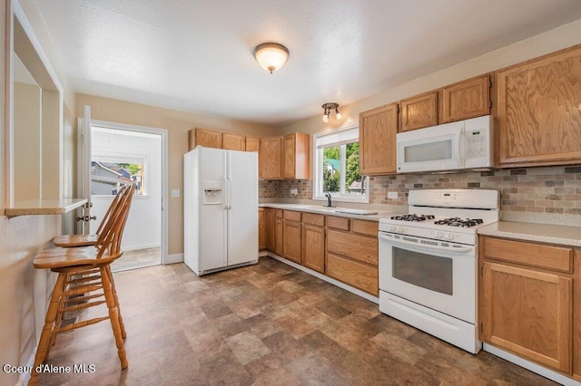 103 3rd St, Wallace, ID 83873 - kitchen featuring white appliances, tasteful backsplash, light countertops, a sink, and baseboards