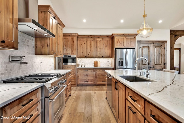 11690 N Arnicas Ct, Hayden, ID 83835 - kitchen featuring appliances with stainless steel finishes, wall chimney exhaust hood, a sink, light stone counters, and recessed lighting