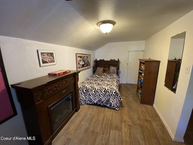 176 King St, Wallace, ID 83873 - bedroom featuring wood finished floors, lofted ceiling, a textured ceiling, and baseboards