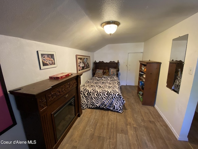 176 King St, Wallace, ID 83873 - bedroom featuring dark wood-type flooring, lofted ceiling, a textured ceiling, and baseboards