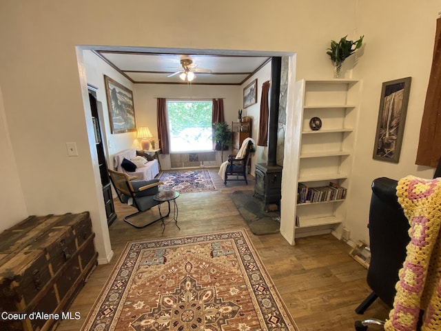 176 King St, Wallace, ID 83873 - living room featuring wood finished floors, a ceiling fan, a wood stove, and ornamental molding