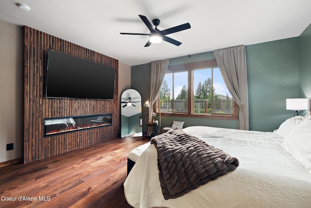 11387 N Armonia Way, Hayden Lake, ID 83835 - bedroom featuring wood finished floors, a glass covered fireplace, and ceiling fan