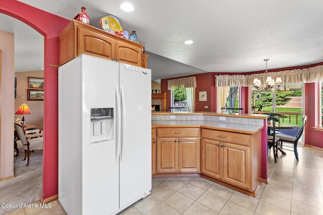 3391 W Loxton Loop, Coeur Dalene, ID 83815 - kitchen featuring white fridge with ice dispenser, light countertops, a peninsula, a chandelier, and recessed lighting