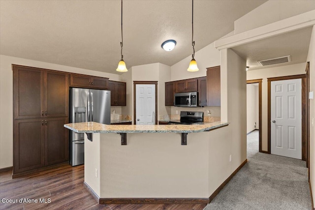 6463 W Conner St, Rathdrum, ID 83858 - kitchen with stainless steel appliances, dark brown cabinetry, a breakfast bar area, a peninsula, and lofted ceiling