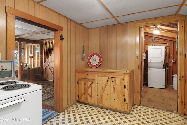 36799 W Coeur D Alene Lake Shr, Coeur Dalene, ID 83814 - kitchen with stacked washing machine and dryer, white electric stove, light flooring, and wood walls