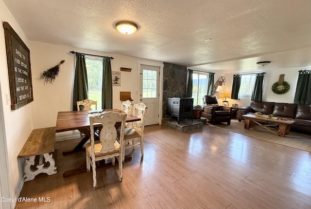 408 Quartz Crk Rd, Priest River, ID 83856 - dining area featuring a textured ceiling, a wood stove, wood finished floors, and healthy amount of natural light
