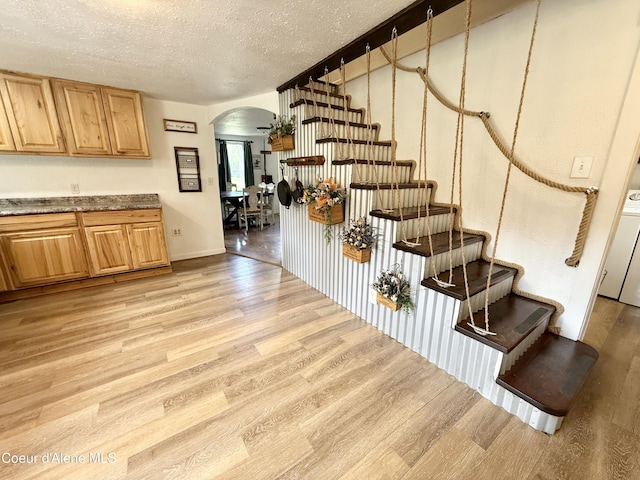 408 Quartz Crk Rd, Priest River, ID 83856 - staircase featuring arched walkways, wood finished floors, a textured ceiling, washer / dryer, and baseboards