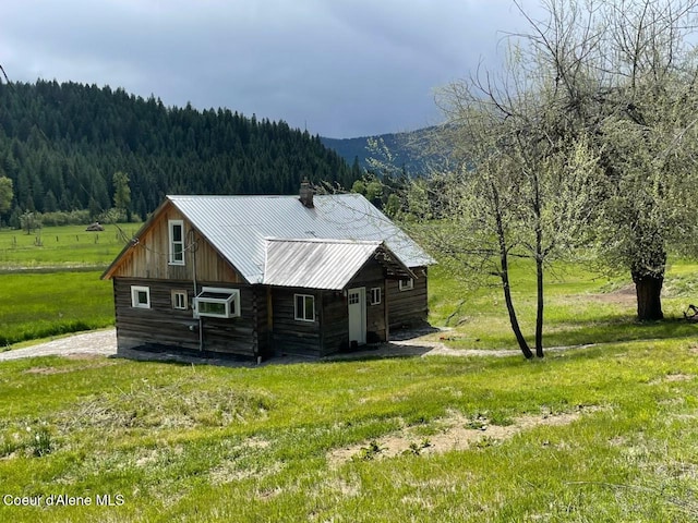 408 Quartz Crk Rd, Priest River, ID 83856 - view of side of home with a forest view, a chimney, metal roof, a yard, and a mountain view